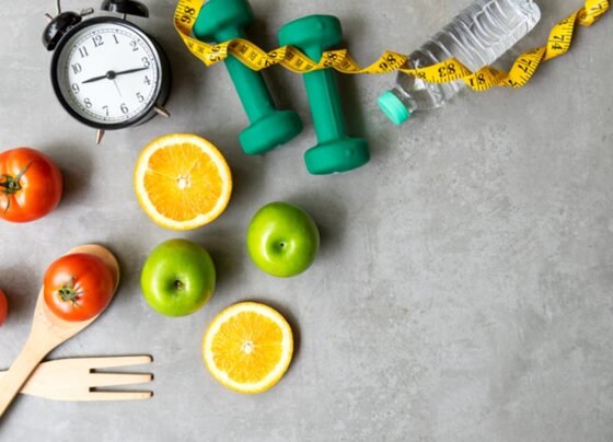 Foto com relógio, frutas, garrafa de água, fita métrica e talheres - Metrópoles