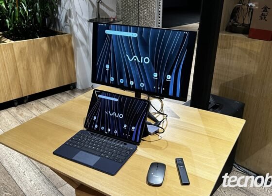 Imagem mostra um tablet Vaio TL12 sobre uma mesa de madeira. Ele é de cor preta e está sendo usado como desktop, com mouse e monitor acoplados. Na parte inferior direita, a marca d'água do "tecnoblog" é visível.
