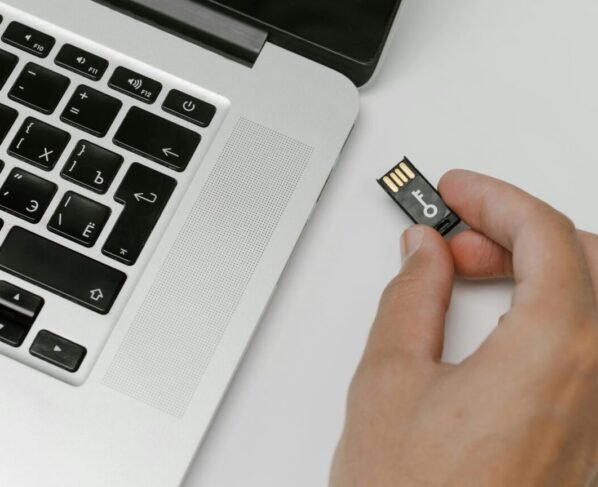 Foto de uma pessoa conectando um pendrive em um notebook branco