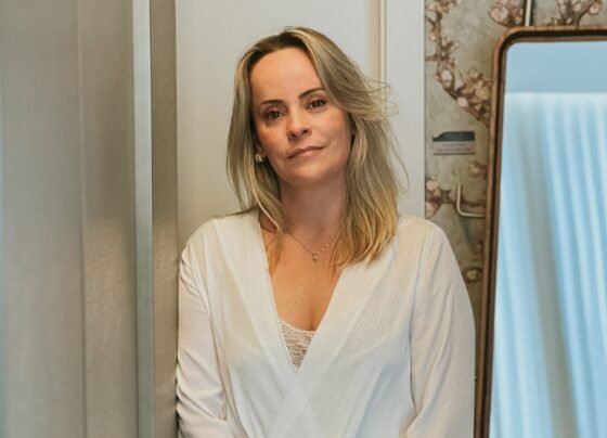 foto colorida de mulher loira posando séria vestida de camisa branca - metrópoles