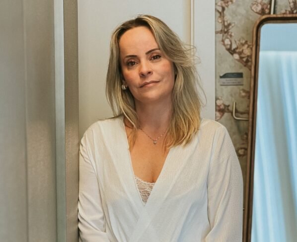 foto colorida de mulher loira posando séria vestida de camisa branca - metrópoles