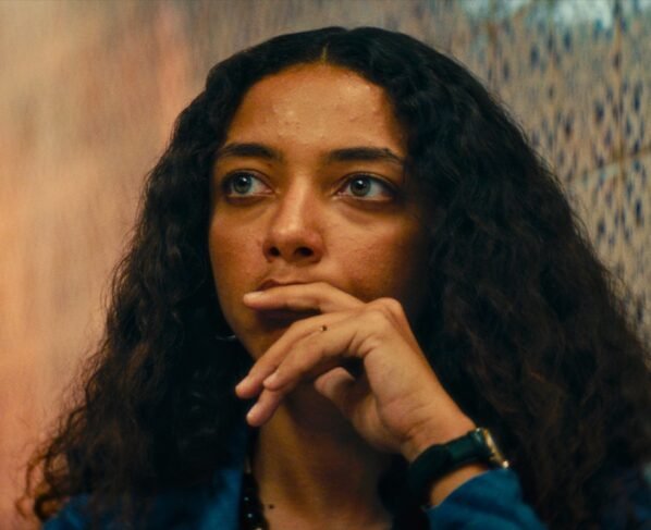 foto colorida do rosto de alice carvalho séria com cabelos cacheados castanhos soltos - metrópoles