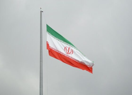 Bandeira do Irã (verde, branca e vermelha, com um emblema islâmico ao centro) hasteada em um dia nublado