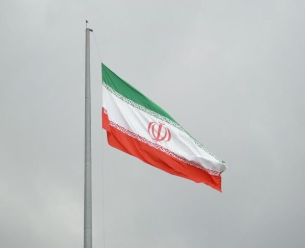 Bandeira do Irã (verde, branca e vermelha, com um emblema islâmico ao centro) hasteada em um dia nublado