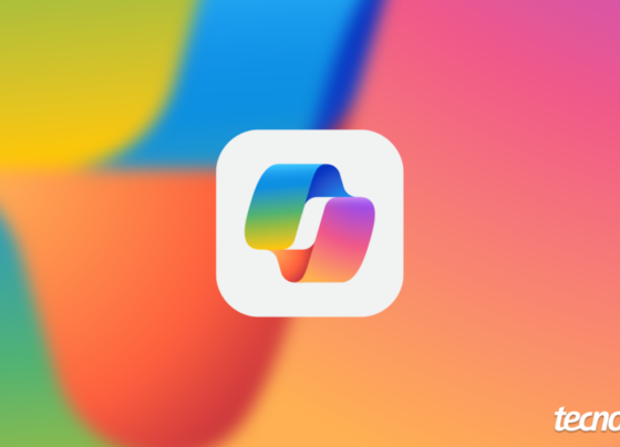 O logo do Microsoft Copilot, composto por quatro formas que se conectam, cada uma em uma cor vibrante (azul, ciano, amarelo e roxo), em um fundo de gradiente suave com as mesmas cores do logo. O logo está centralizado em um quadrado branco com bordas arredondadas. No canto inferior direito, a marca d'água "tecnoblog" é visível.