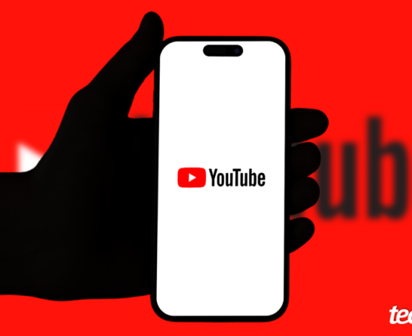 Mão segurando um celular que exibe o YouTube, com um fundo de cor vermelha. Na parte inferior direita, está o logotipo do "tecnoblog".
