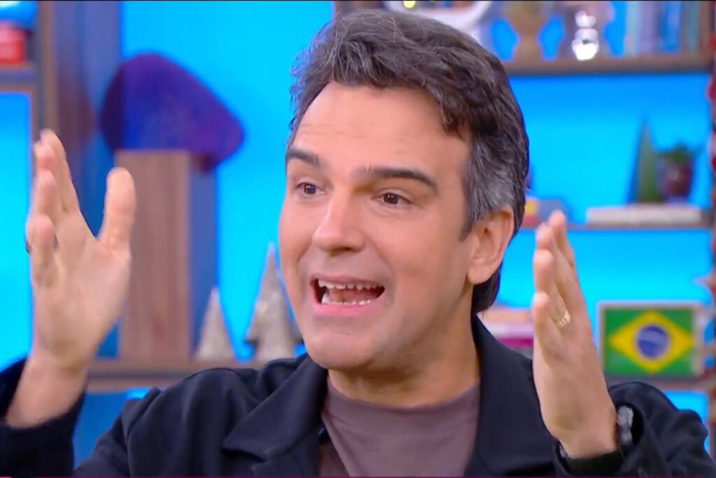 Tadeu Schmidt gesticulando com as mãos no cenário do BBB 25 - Metrópoles