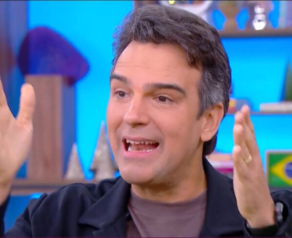 Tadeu Schmidt gesticulando com as mãos no cenário do BBB 25 - Metrópoles