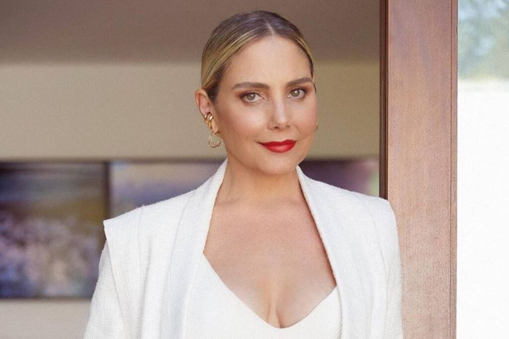 foto de uma mulher loira, branca, usando batom vermelho. ela usa look branco - Metrópoles